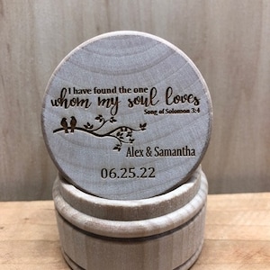 May include: A wooden ring box with a lid that has a quote engraved on it: "I have found the one whom my soul loves - Song of Solomon 3:4". The lid also has a small tree with two birds and the names "Alex & Samantha" and the date "06.25.22" engraved on it.