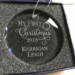 May include: A clear glass Christmas ornament with the text "My First Christmas 2018" and the name "Kerrigan Leigh" engraved on it.