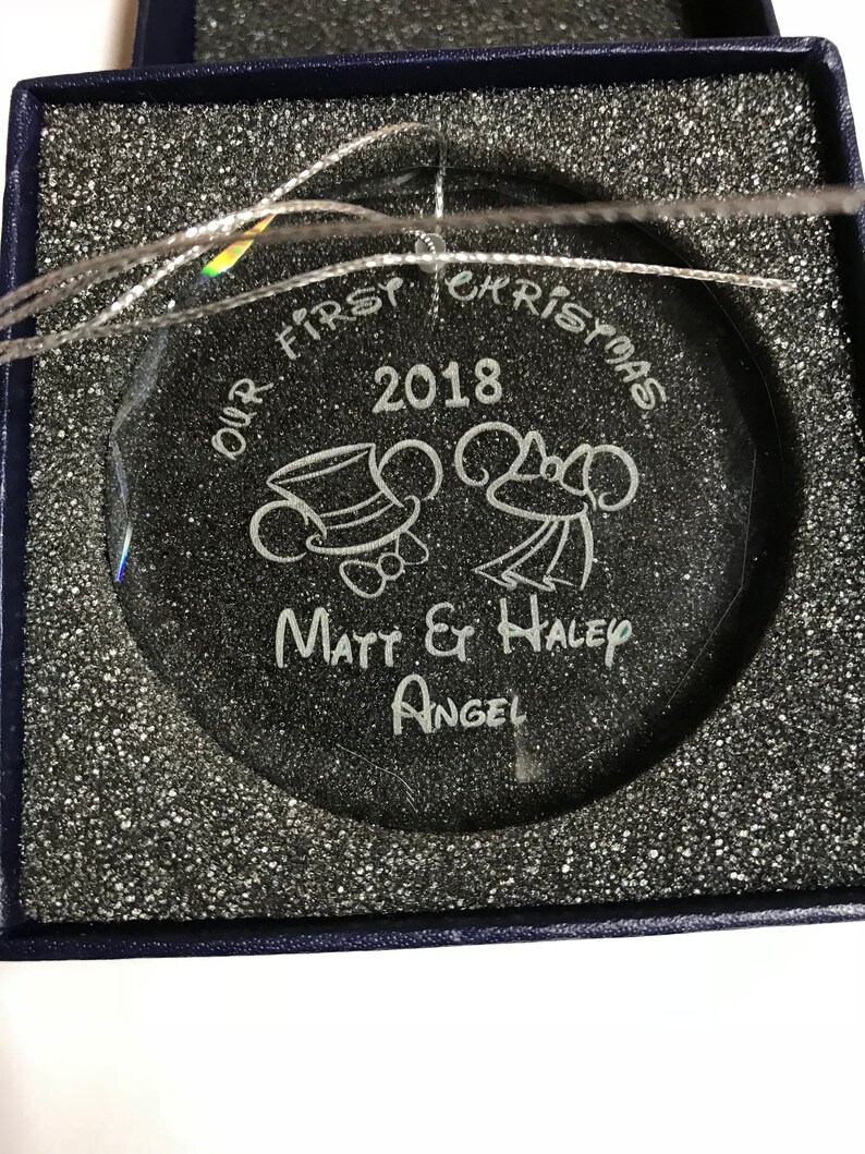 Pu&ograve; includere: Un ornamento natalizio trasparente inciso con la scritta "OUR FIRST CHRISTMAS 2018" e i nomi "Matt & Haley Angel". L'ornamento &egrave; rotondo e viene fornito in una scatola blu con un filo d'argento per appenderlo.