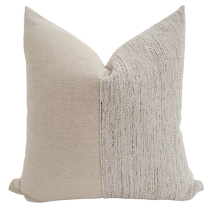 May include: A cream-colored throw pillow with a textured woven design on one side and a smooth fabric on the other side.