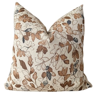 May include: A decorative throw pillow with a cream background and a brown and blue floral pattern.
