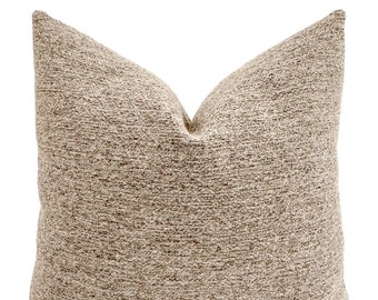May include: A beige throw pillow with a textured woven fabric. The pillow is square shaped and has a simple design.