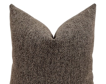 May include: A brown and beige herringbone patterned throw pillow.
