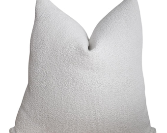 May include: A white, fluffy throw pillow with a textured surface.