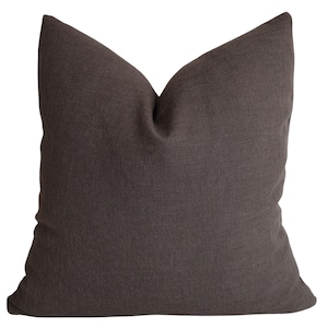 May include: A solid, dark brown decorative pillow with a textured fabric. The square pillow has a simple, classic design, suitable for various home decor styles. The pillow is a neutral color, making it versatile for different color schemes.