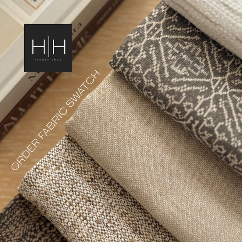 May include: A stack of four fabric swatches featuring a dark gray textile with a white geometric pattern, a solid beige linen-like fabric, a textured brown and cream woven material, and a white fabric. Text reads ORDER FABRIC SWATCH.