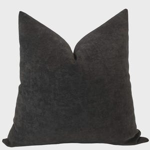 May include: A dark gray decorative pillow with a textured surface. The pillow has a square shape with a pointed top and is made of a soft, plush material. The pillow is designed for home decor and adds a touch of elegance to any living space.