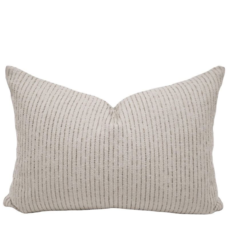 May include: A rectangular throw pillow featuring a textured off-white fabric base with vertical stripes in a muted grey tone. The pillow has a soft, slightly plumped appearance with a consistent woven pattern across the entire front surface.