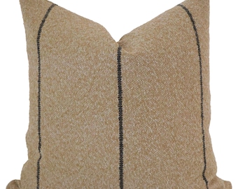 May include: A tan throw pillow with black stripes. The pillow is made of a soft, textured fabric.
