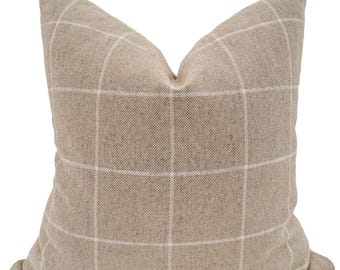 May include: A beige throw pillow with a white grid pattern. The pillow is made of a soft, textured fabric.