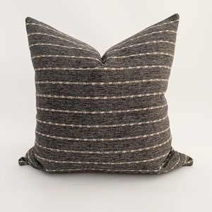 May include: A black and white striped throw pillow with a subtle woven texture. The pillow is filled with a soft, comfortable material and is perfect for adding a touch of style to any room.