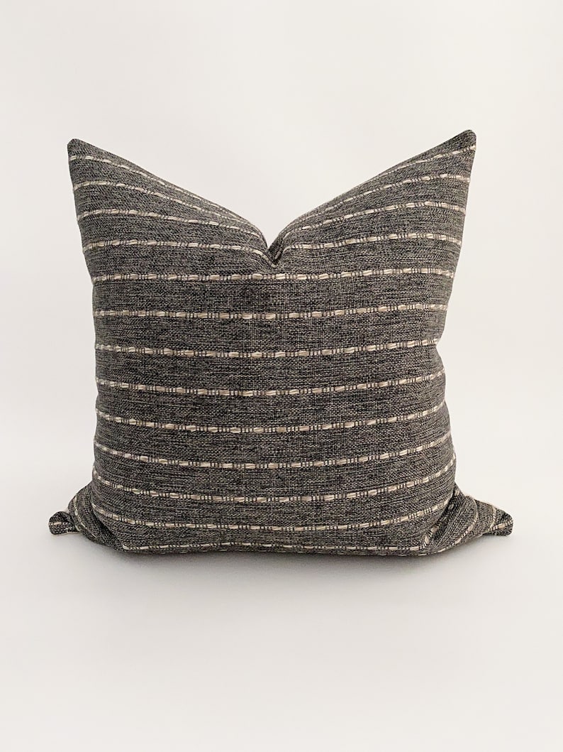May include: A black and white striped throw pillow with a subtle woven texture. The pillow is filled with a soft, comfortable material and is perfect for adding a touch of style to any room.