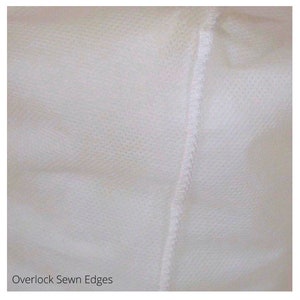 May include: Close-up of a white fabric with an overlock stitch along the edge. The fabric has a textured surface. "Overlock Sewn Edges" is written in black text at the bottom of the image.