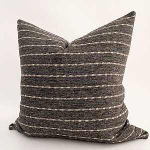 May include: A gray and white striped throw pillow with a subtle woven texture. The pillow is made of a soft, comfortable fabric and is perfect for adding a touch of style to any room.