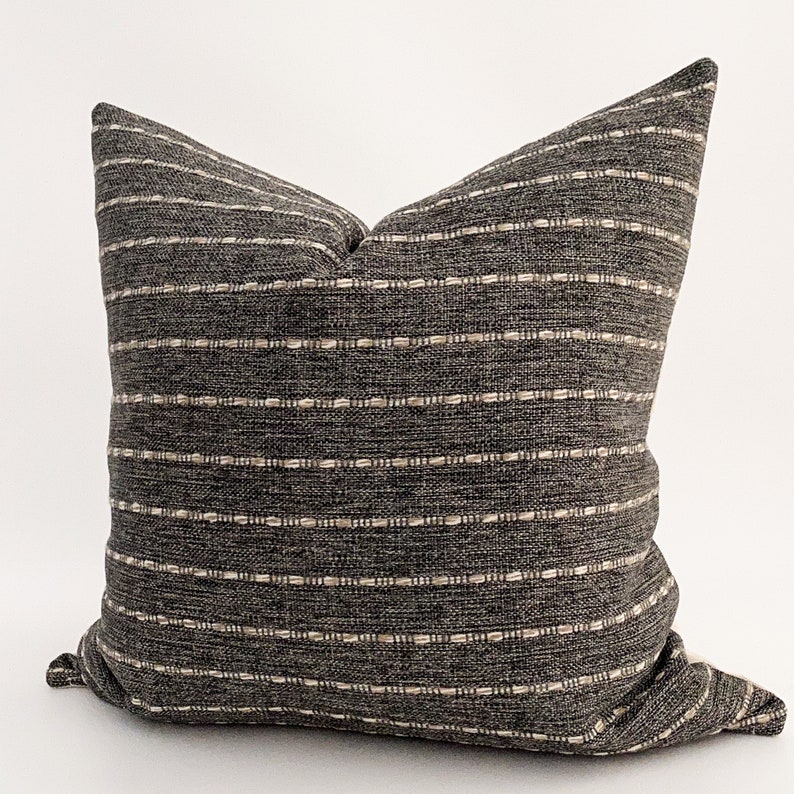 May include: A gray and white striped throw pillow with a subtle woven texture. The pillow is made of a soft, comfortable fabric and is perfect for adding a touch of style to any room.