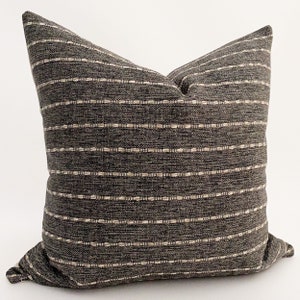 May include: A gray and white striped throw pillow with a subtle woven texture. The pillow is made of a soft, comfortable fabric and is perfect for adding a touch of style to any room.