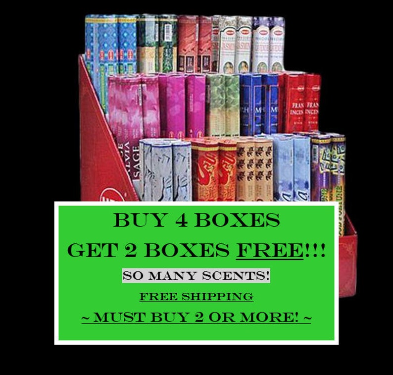 May include: A display of incense boxes in various colours, including blue, pink, red, and green. The boxes are arranged in a tiered display with a red cardboard backing. A green sign with white text reads "BUY 4 BOXES GET 2 BOXES FREE!!!"