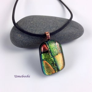 May include: A green, gold, and red dichroic glass pendant with copper bail on a black cord necklace.