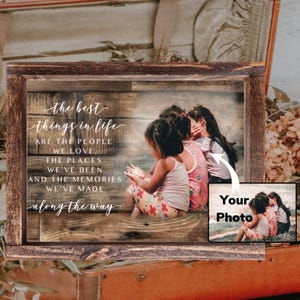 May include: A framed photograph with the inscription "the best things in life are the people we love, the places we've been and the memories we've made along the way." The image shows three children.