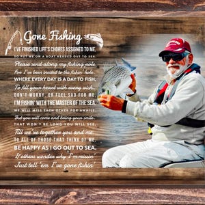K&ouml;nnte beinhalten: Ein rechteckiges Wandbild mit Holzrahmen, das ein aufgedrucktes Bild einer Person mit roter Kappe und heller Kleidung zeigt, die einen Fisch h&auml;lt. Der Text lautet Gone Fishing sowie ein Gedicht &uuml;ber das Angeln auf dem Meer.