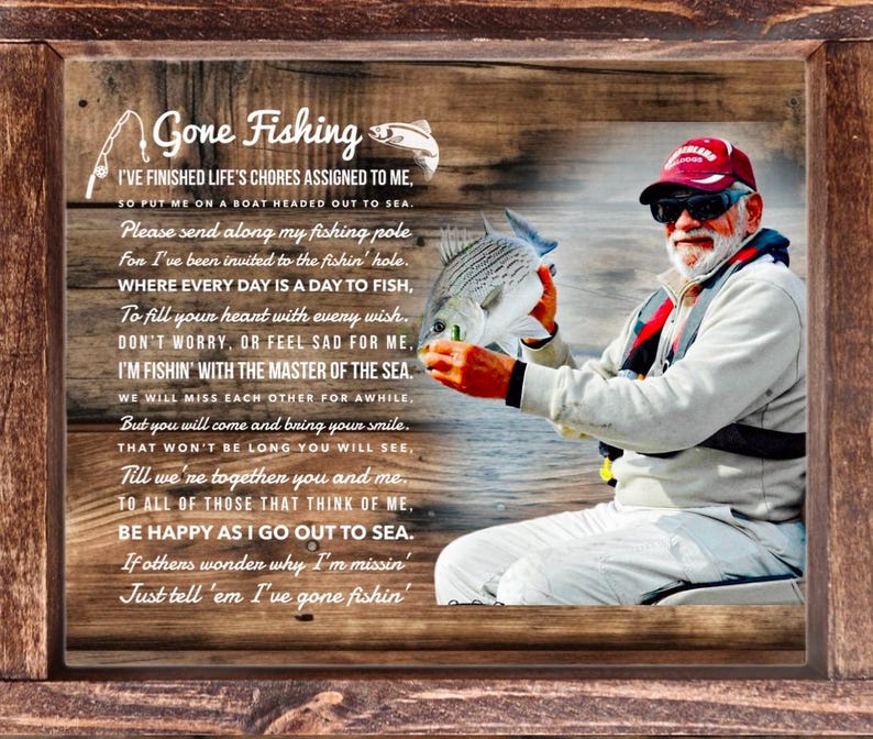 K&ouml;nnte beinhalten: Ein rechteckiges Wandbild mit Holzrahmen, das ein aufgedrucktes Bild einer Person mit roter Kappe und heller Kleidung zeigt, die einen Fisch h&auml;lt. Der Text lautet Gone Fishing sowie ein Gedicht &uuml;ber das Angeln auf dem Meer.