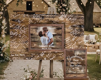 May include: A large rectangular wooden guestbook sign featuring a central photograph of a couple with the text Ashleigh & Jordan May 29, 2026, surrounded by handwritten white ink signatures, paired with a smaller matching sign reading Guestbook.