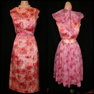 May include: Two vintage dresses with a pink and red rose print. The dress on the left is a sleeveless, fitted dress with a scoop neck. The dress on the right is a sleeveless, A-line dress with a ruffled collar.