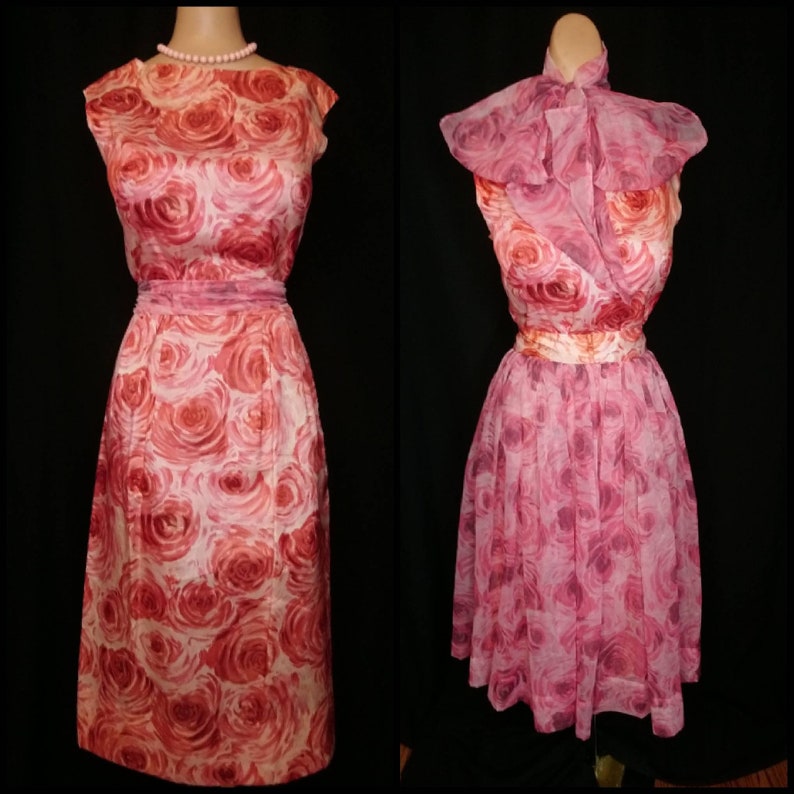 May include: Two vintage dresses with a pink and red rose print. The dress on the left is a sleeveless, fitted dress with a scoop neck. The dress on the right is a sleeveless, A-line dress with a ruffled collar.