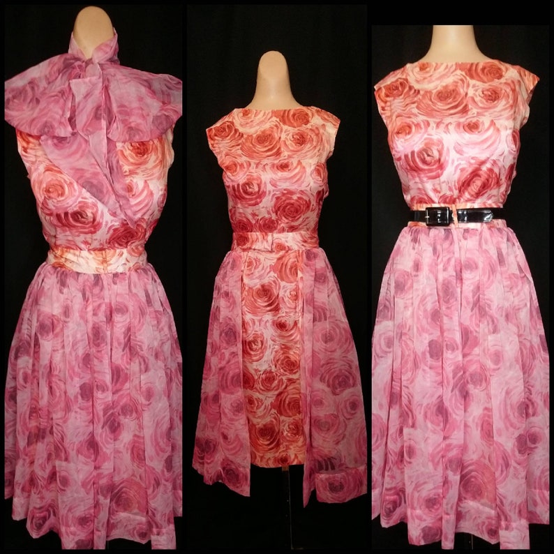 May include: A pink and red floral print dress with a sheer overlay and a matching sash. The dress has a fitted bodice and a full skirt.