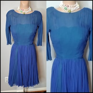 Puede incluir: Un vestido vintage azul con falda plisada y escote redondo. El vestido tiene mangas tres cuartos y está hecho de una tela transparente.