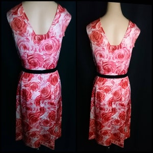 May include: A sleeveless dress with a pink and red floral print. The dress has a V-neckline and a black belt.