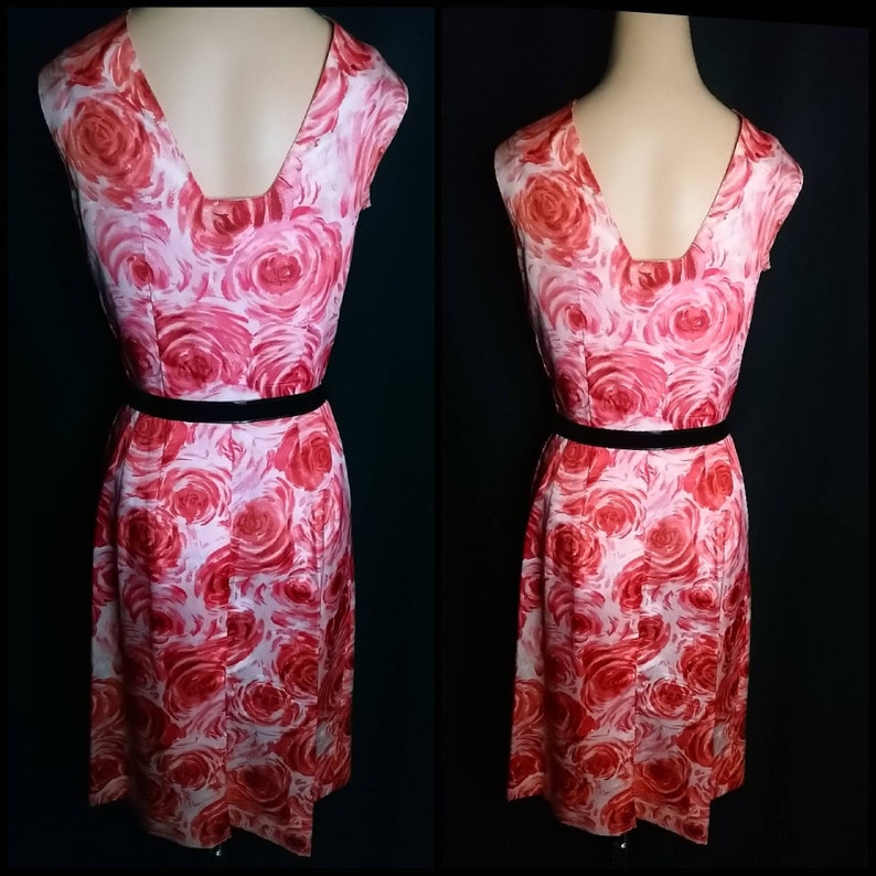 May include: A sleeveless dress with a pink and red floral print. The dress has a V-neckline and a black belt.