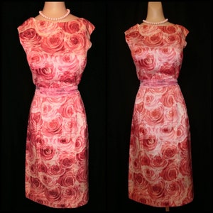 May include: A pink sleeveless dress with a rose print. The dress has a bateau neckline and a fitted silhouette.