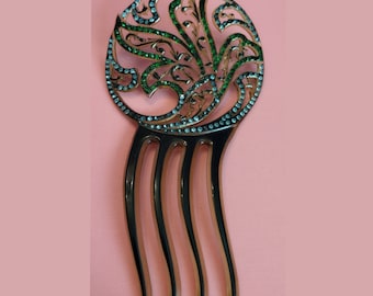 May include: A brown plastic hair comb with a decorative, round, green and clear rhinestone design.