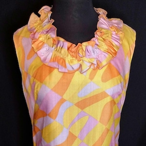 Peut inclure: Une robe sans manches avec un motif géométrique rose et orange. La robe a un col à volants.