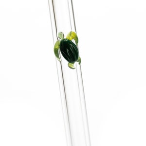 May include: A clear glass drinking straw with a green and yellow glass turtle design at the top.