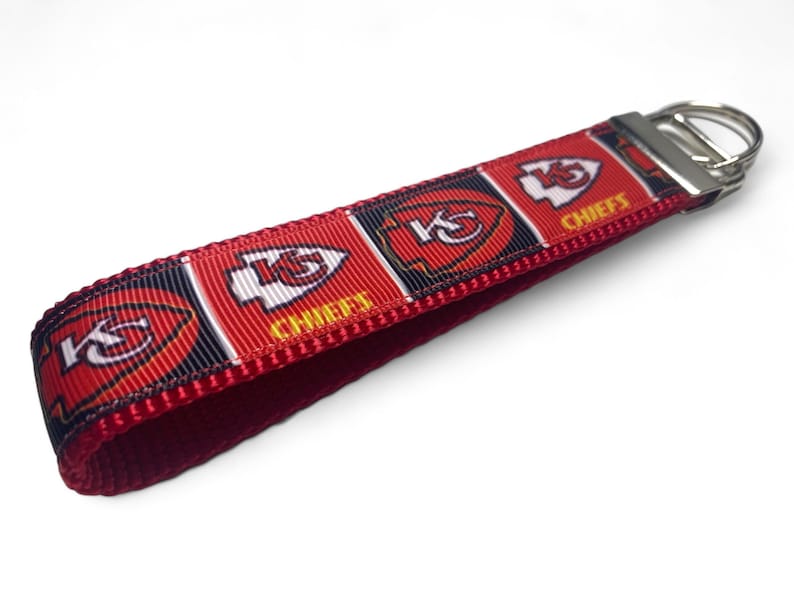 May include: Red, white, and black key chain with the Kansas City Chiefs logo and the word "Chiefs" repeated on the ribbon. The key chain has a silver metal key ring.