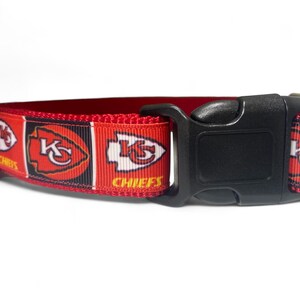 May include: Red, black, and white dog collar with a Kansas City Chiefs logo. The collar has a black plastic buckle.
