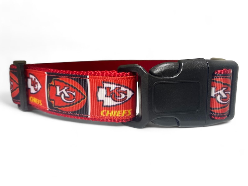 May include: Red, black, and white dog collar with a Kansas City Chiefs logo. The collar has a black plastic buckle.