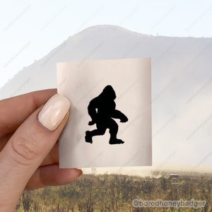 May include: A black silhouette of Bigfoot walking on a white background.