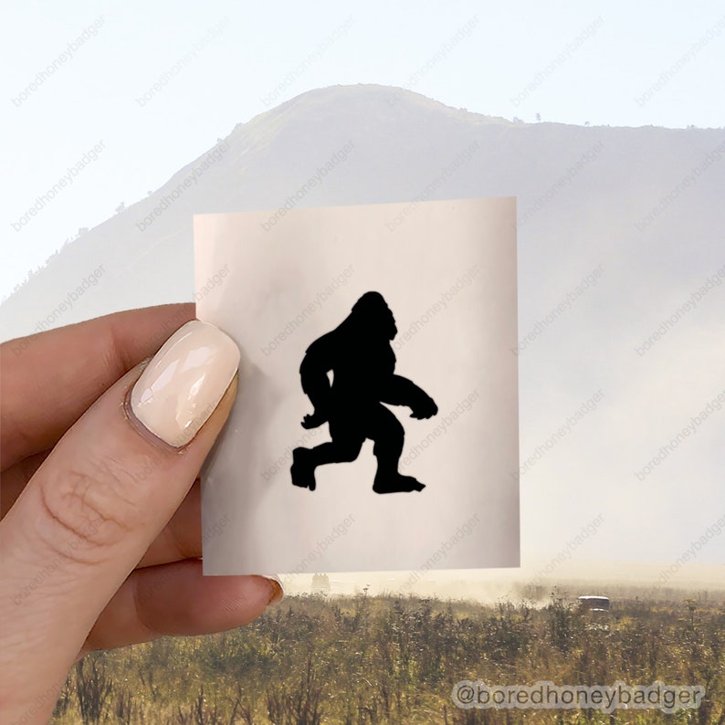 May include: A black silhouette of Bigfoot walking on a white background.