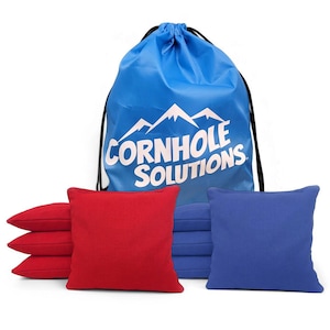 May include: A cornhole game set featuring red and blue bean bags, a blue drawstring bag with the text "CORNHOLE SOLUTIONS" and a mountain graphic. The bean bags are square and appear to be made of a durable fabric.