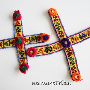 May include: Two colorful beaded headbands with tassels. The headbands are yellow, orange, blue, green, and red. The tassels are pink and green.