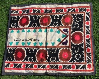 May include: A white cotton rug with a black, red, and brown embroidered design. The rug is 126 x 105 cm and features a geometric pattern with floral motifs.