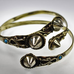 May include: A double-strand silver and brass bracelet with turquoise accents. The bracelet features decorative, pointed, silver-toned accents.