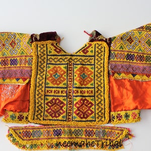 Könnte beinhalten: Ein lebendiges, handgefertigtes Textil mit aufwendiger Perlenarbeit und Stickerei. Das Stück zeigt geometrische Muster in Gelb, Rot und Blau, umgeben von orangefarbenem und grünem Stoff. Der Text "neemaheTribal" ist sichtbar.