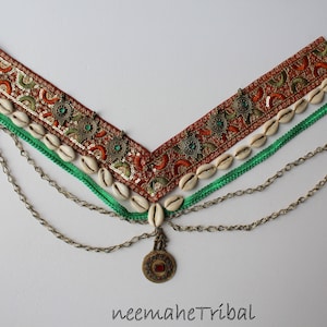 May include: A brown and gold beaded headband with green and orange accents, white seashells, and a gold chain with a pendant. The headband is decorated with sequins and embroidery. The text "neemaheTribal" is visible at the bottom of the image.