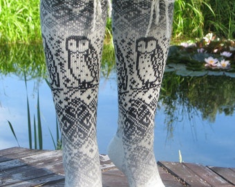 May include: A pair of white and black knee-high socks with an owl pattern. The socks are made of a soft, knitted fabric and have a white lace trim at the top.