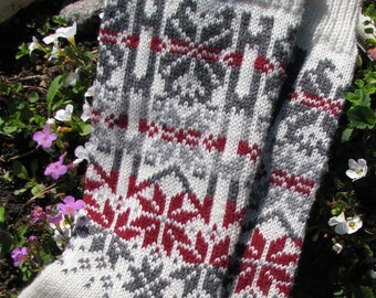 Könnte beinhalten: Ein Paar weiße Stricksocken mit einem grauen und roten Schneeflockenmuster.