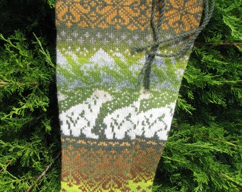 May include: Green, brown, and white patterned knitted socks with a green yarn tie. The socks have a geometric design with a mountain scene.
